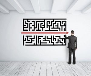 businessman drawing maze on white wall
